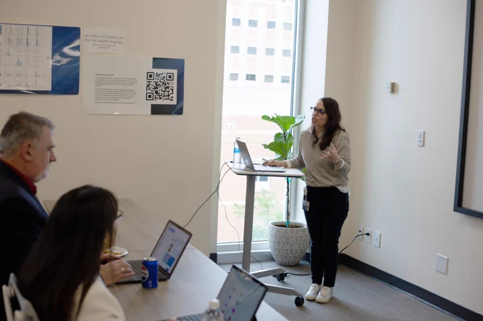 [ID: Pictured is a photo of people listening to a presentation during a workshop in the Day Family Research Lab.]