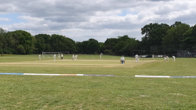 View from boundary at Fernhursy shows fielders surrounding batter