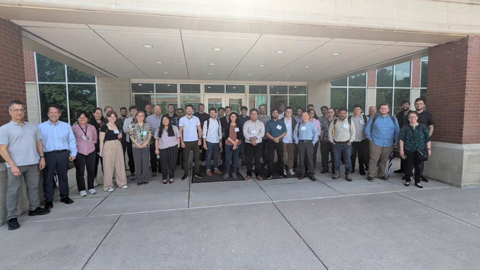 Group of professionals standing in front of an office building on a sunny day.