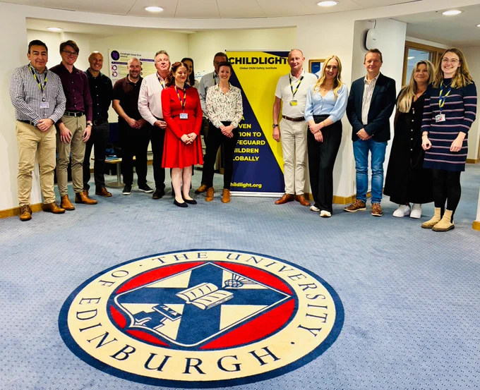 Members of the Childlight, CRC and Lantern Rescue teams pose for a picture next to a Childlight branded banner. 