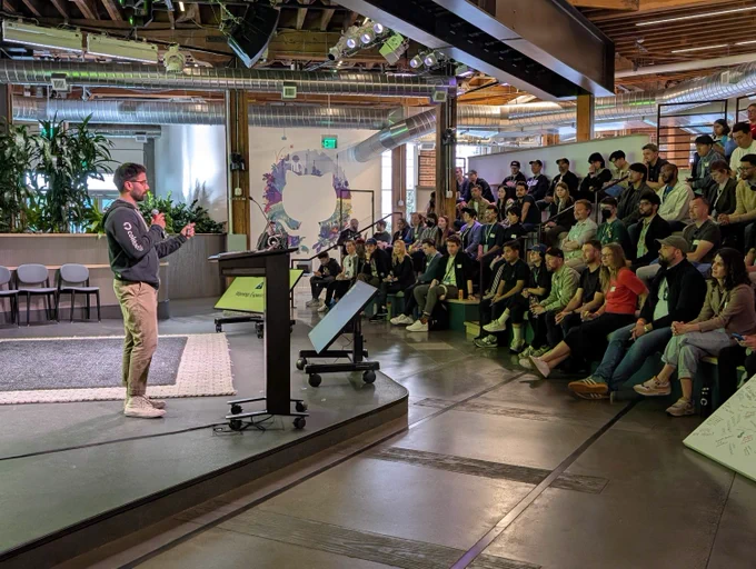 Cole Bemis giving a talk on stage in front of audience of developers and designers 