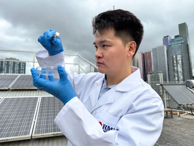Dr Derek Hao holding a spongy cube with tweezers with one hand and a petri dish in the other while he examines the spongy cube.