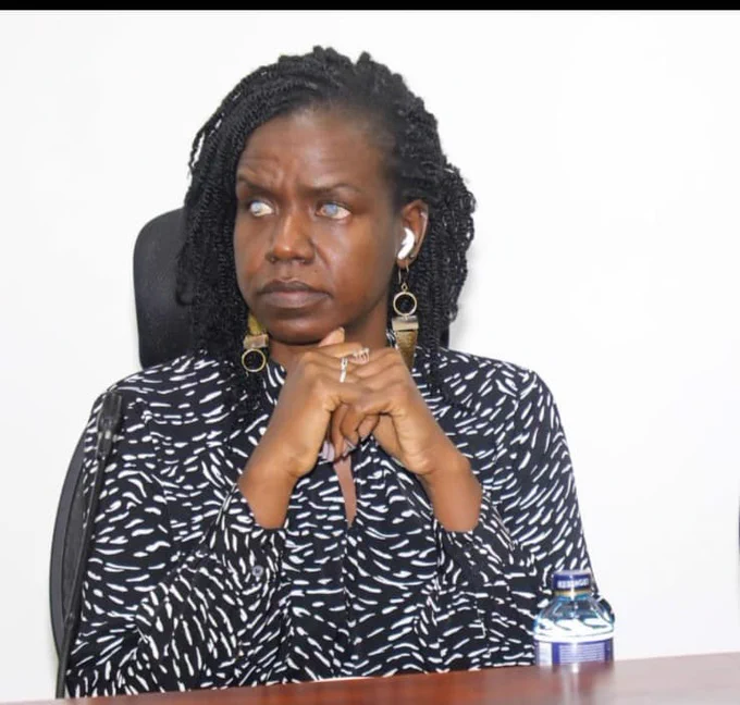 Image of Senator Crystal Asige, seated in a black executive chair. She is dressed in a black long-sleeved shirt with white polka dots. Her hair is styled in an afro and laid downwards.