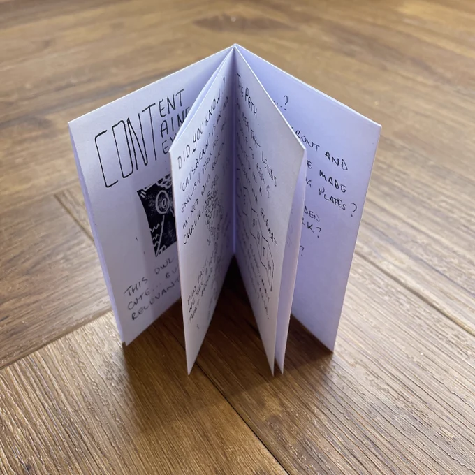The image shows a small handmade zine, open to display its pages. The zine is titled "CONTENT" on the front, with a black-and-white illustration of a snack package. The pages feature handwritten notes and doodles, with phrases such as "DID YOU KNOW?" and questions about food, eating habits, and possibly related topics like travel. The zine is folded and placed on a wooden surface, giving it a homemade, artistic feel.