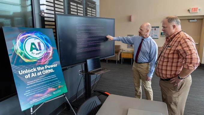 Two individuals examining code on a monitor at an AI exhibition at Oak Ridge National Laboratory.