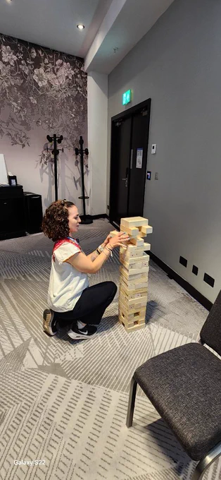 A person crouching playing Jenga.