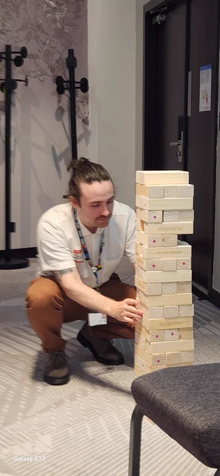 A person crouching playing Jenga.