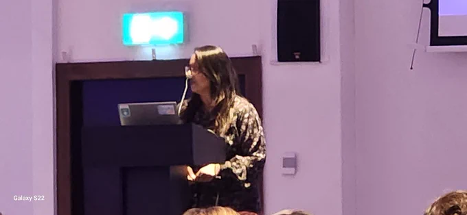 Woman talking on a stage behind a podium.