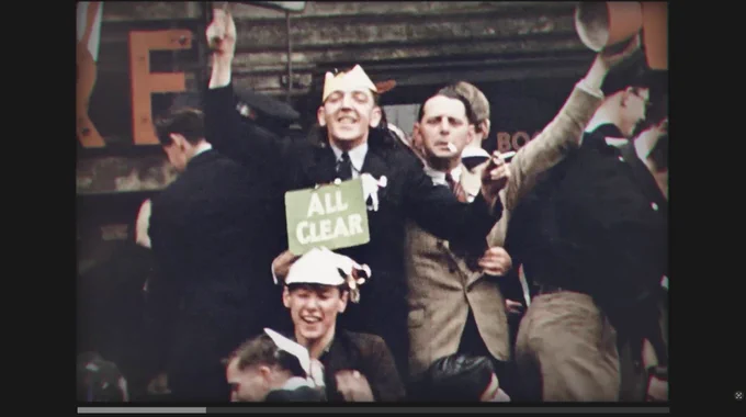 AY-PE AV design - Imperial War Museum London WWII End of War: Londoners celebrate Victory in Europe Day holding an 'ALL CLEAR' sign