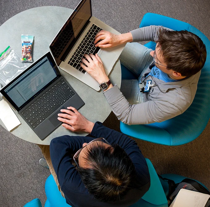 two people working on laptops, viewed from above