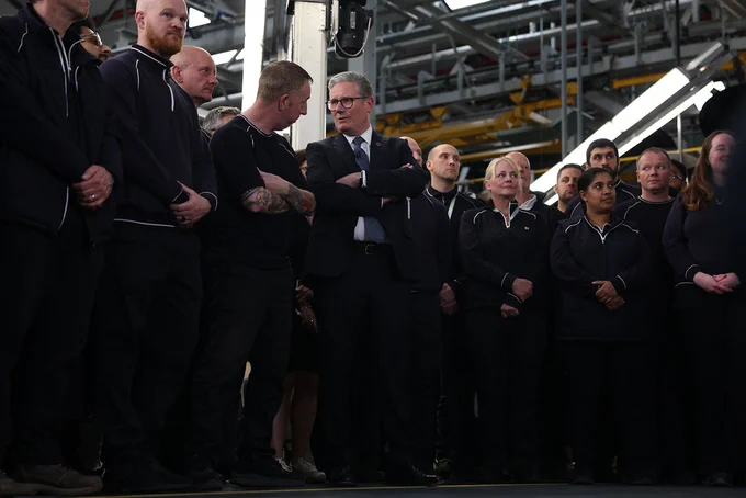 Prime Minister Keir Starmer stands next to workers at Jaguar Land Rover.