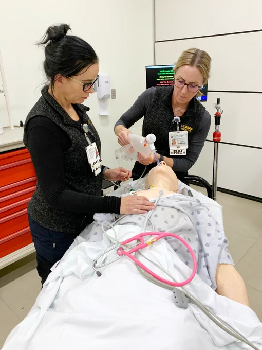 Two nurses from the Pediatric Transport Team provide airway support for a simulation mannequin during a simulation scenario. 