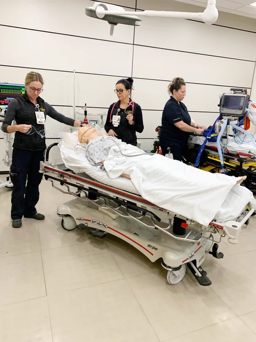 Three nurses with the Pediatric Transport Team provide airway support to a mannequin during a simulation exercise.