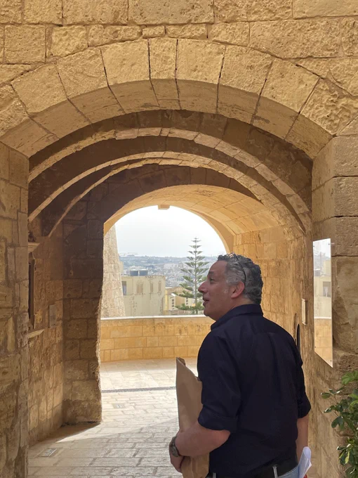 Professor Eric Tagliacozzo walks through a stone archway in Malta.