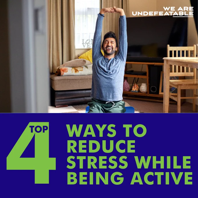Individual stretching in a living room, with text overlay reading 'Top 4 Ways to Reduce Stress While Being Active' as part of the 'We Are Undefeatable' campaign.