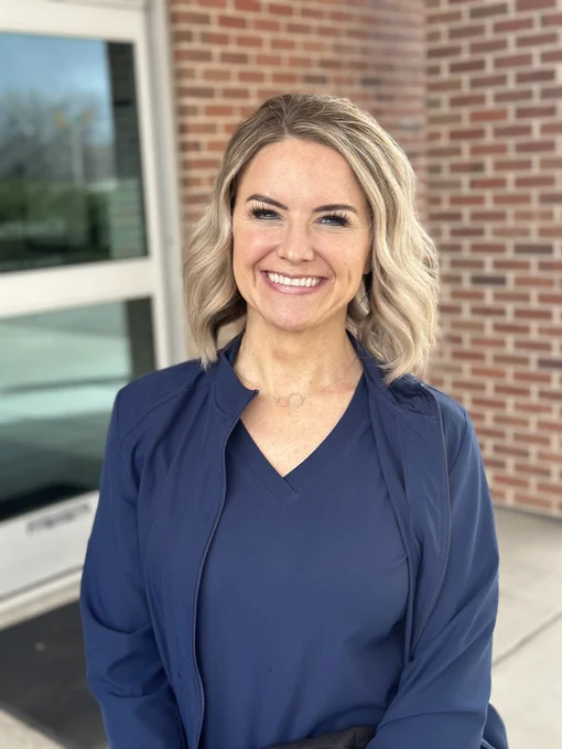 Gina Corry, wearing navy blue scrubs and a jacket, smiles outside a Utah emergency center.
