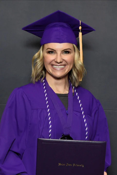 Gina Corry, wearing a purple graduation cap and gown, smiles at her nursing school graduation from Weber State University.