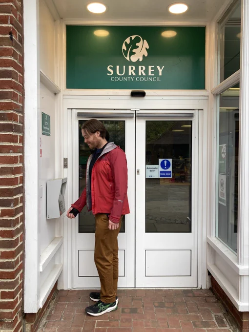 Super Access user holding library card to reader to enter Dorking Library