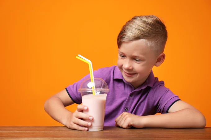A boy looks holds a strawberry milkshake