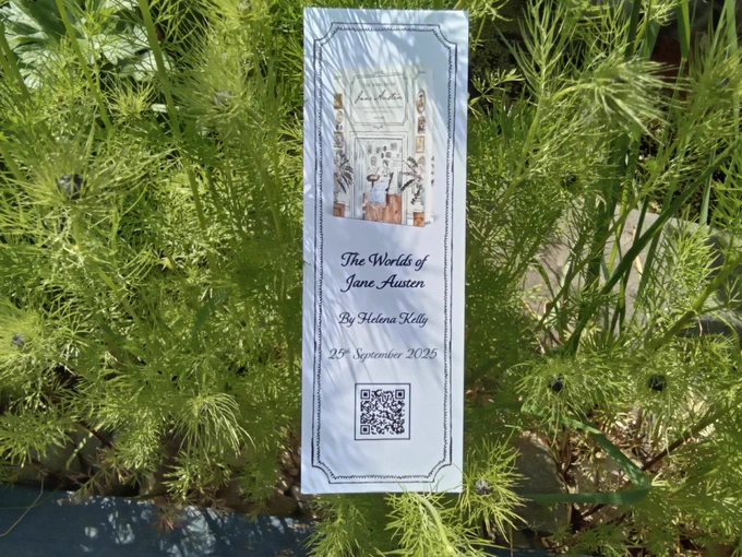 A pale blue promotional bookmark, against a background of love-in-the-mist. On it are a small image of a book and a QR code.