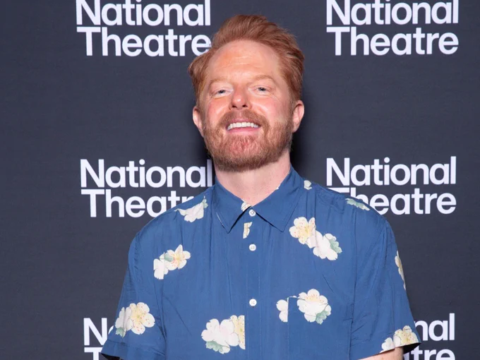 Person smiling, standing in front of a National Theatre backdrop, wearing a blue floral shirt.