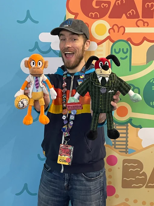 Smirky smiling and holding Doctor Surlee and Lord Lowden Clear plushies at the Child’s Play booth during PAX East 2025!