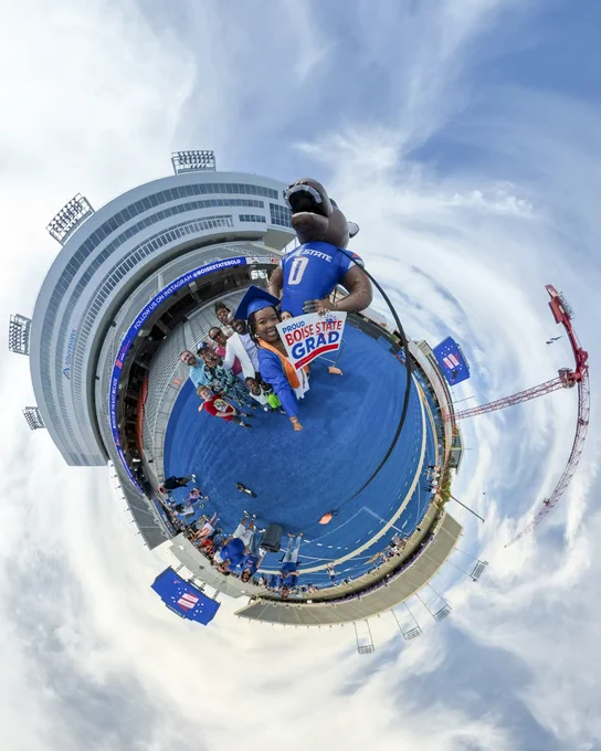 A tiny planet photo of Boise State graduates with friends and family on the blue turf inside Albertsons Stadium.