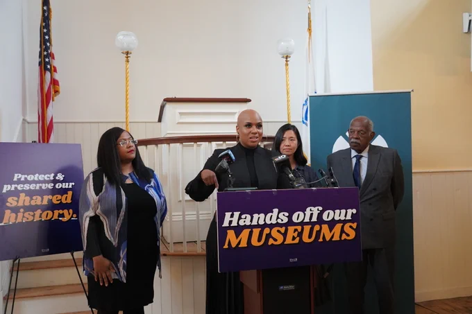 Rep. Ayanna Pressley stands behind a podium delivering remarks at the Boston Museum of African American History.