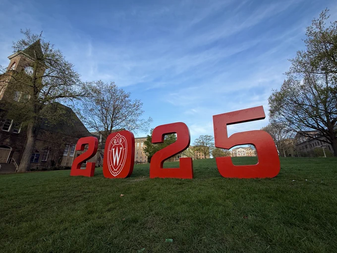 Photo of large, red 2025 numbers at the base of Bascom Hill at sunrise.