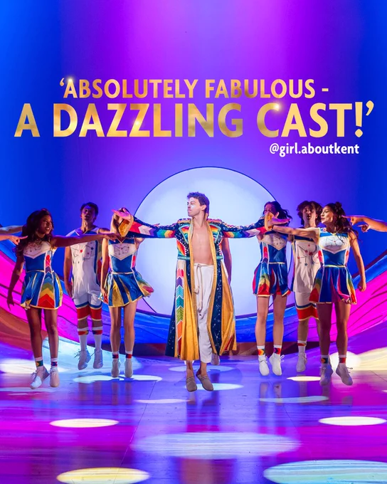 A promotional photo for Joseph and the Amazing Technicolor Dreamcoat, featuring a central performer in a colourful robe surrounded by dancers in cheerleading costumes, under a bright stage light with the text 'Absolutely Fabulous - A Dazzling Cast!' and the credit @girl.aboutkent.