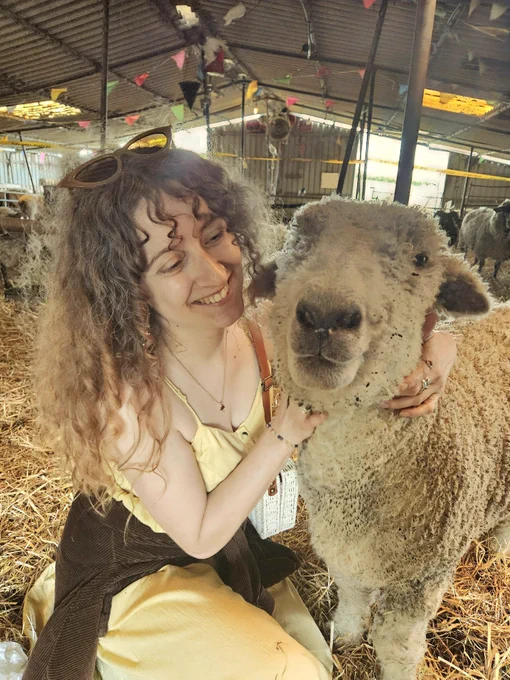 A smiling person embraces a friendly sheep