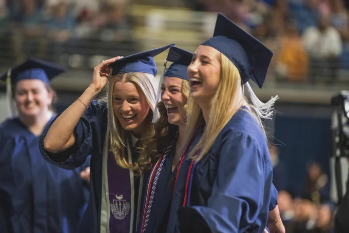 Group of graduates laughing in caps and gowns 