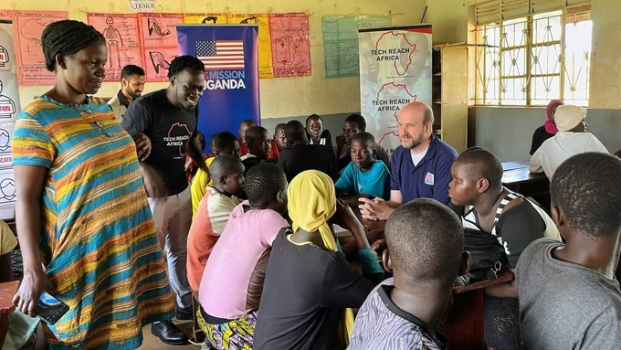 Ambassador Popp visits U.S. Exchange Alumnus Ntende Baker, along with students and their teachers, at the TechReachAfrica mobile computer labs.