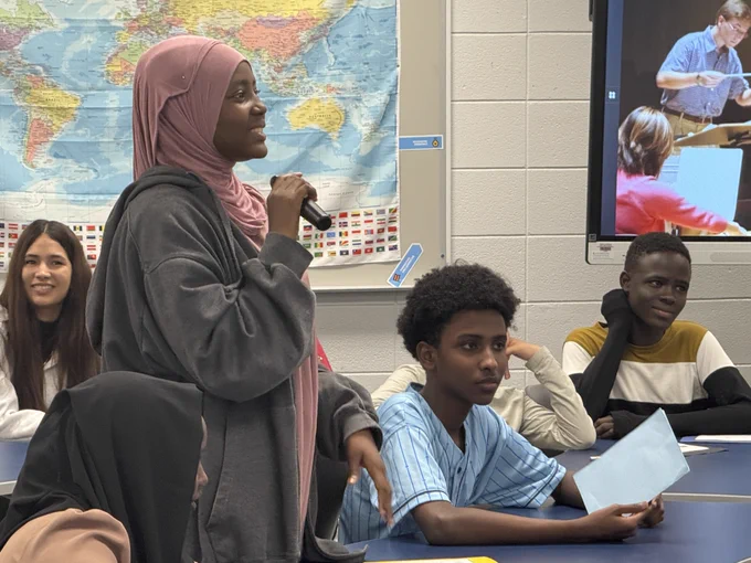 A student smiles and holds a microphone.