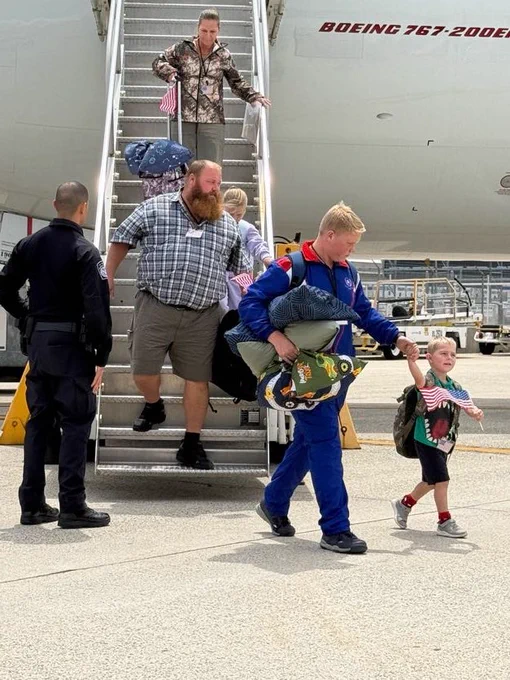 Refugees disembark airplane carrying American flags