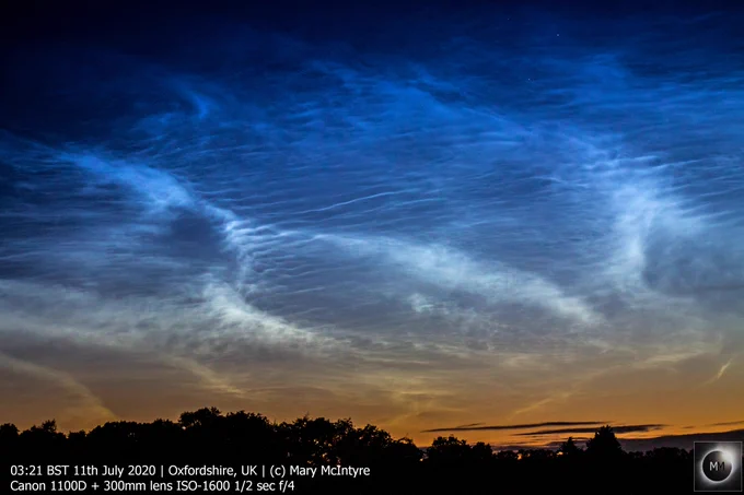 Electric blue and white wisps of noctilucent clouds shining through the dawn twilight