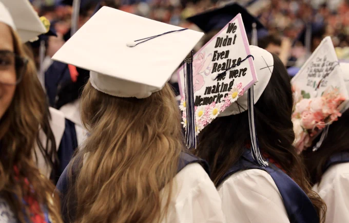 A graduate wears a cap that says, "We didn't even realize we were making memories."