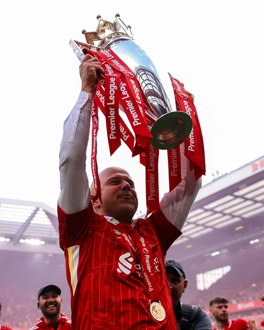 Photography of Arne Slot raising the Premier League trophy.
