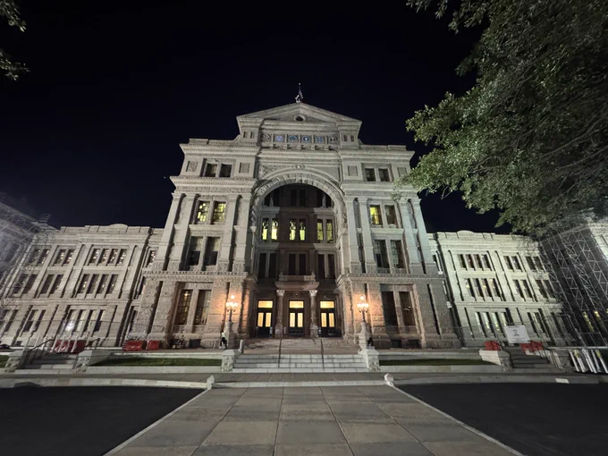 Shot of the south front of the Texas state Capitol at night with lots of lights on in the building.