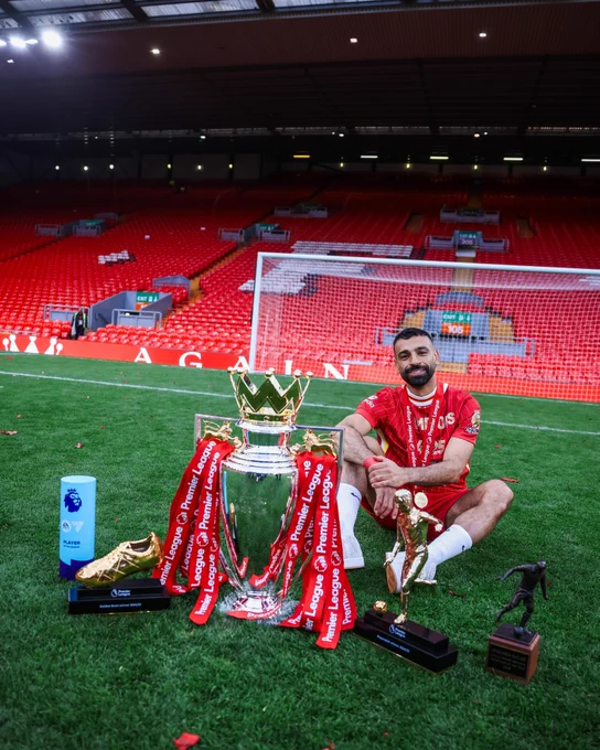 Photography of Mo Salah with his awards and trophies from the season.