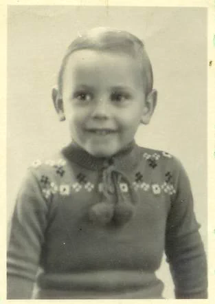 Vintage black and white photo of a smiling young boy in a patterned sweater.
