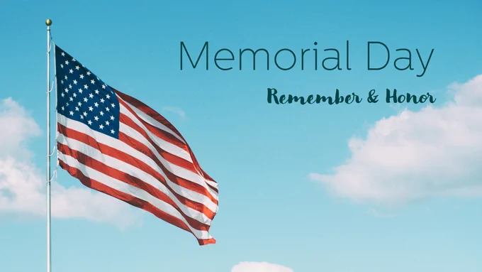 American flag waving under a blue sky with clouds, with the words 'Memorial Day - Remember & Honor' displayed.