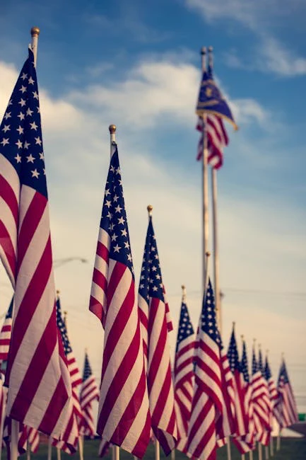 Multiple American flags waving in the wind against a blue sky, symbolizing patriotism.