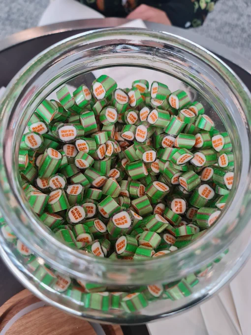Green and orange lollies in a bowl that are customised with APPS2025. 