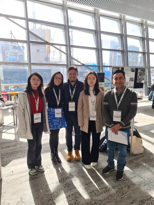 A group of 5 people standing together and smiling
