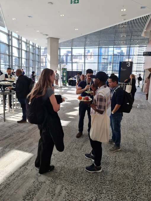 A group of four people talking in the foyer and eating together at lunch time. 