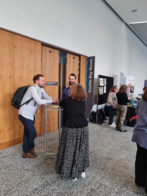 Three people talking and standing around a table. 