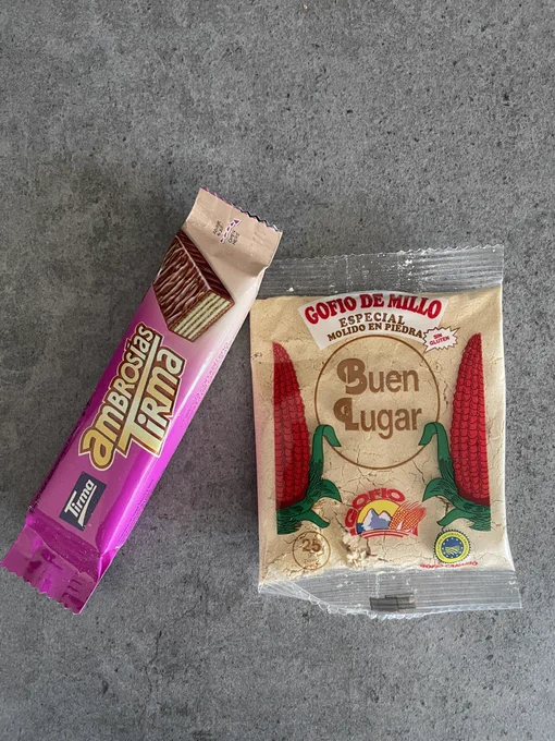Foto de una chocolatina Ambrosía Tirma y un sobrecito de gofio de maíz.
