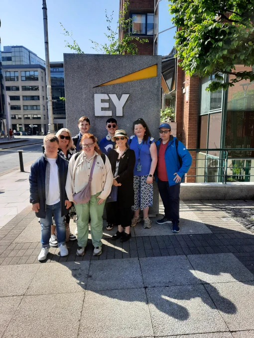 A group of TCPID students and staff standing outside by a large EY sign