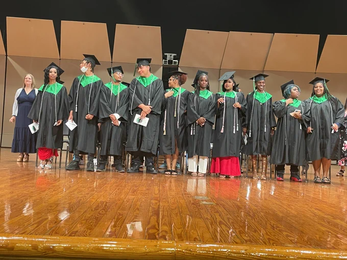 Graduates stand on stage.